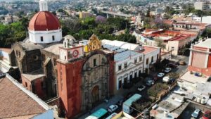Mesa de desayuno al aire libre en Cuernavaca con café, fruta y pan artesanal, rodeada de vegetación y luz natural.