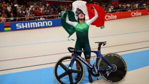 Yareli Acevedo celebra su victoria en el Mundial de Ciclismo en pista en Santiago de Chile con la bandera de México.