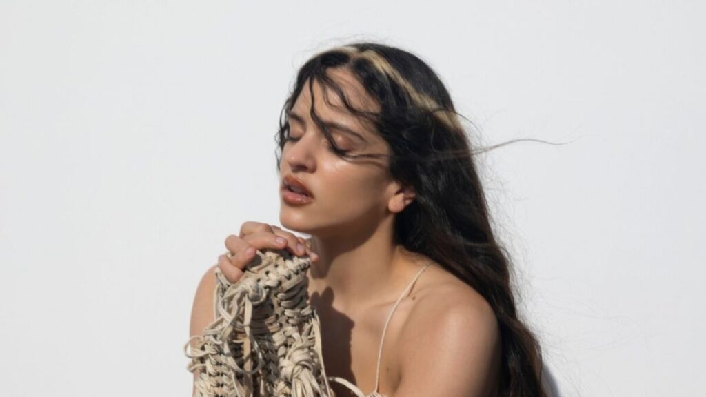 Retrato artístico de Rosalía en un escenario minimalista con estética teatral y luces suaves inspirado en su Lux Tour experimental