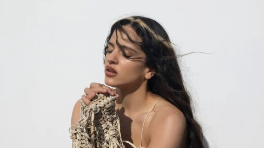 Retrato artístico de Rosalía en un escenario minimalista con estética teatral y luces suaves inspirado en su Lux Tour experimental