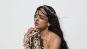 Retrato artístico de Rosalía en un escenario minimalista con estética teatral y luces suaves inspirado en su Lux Tour experimental