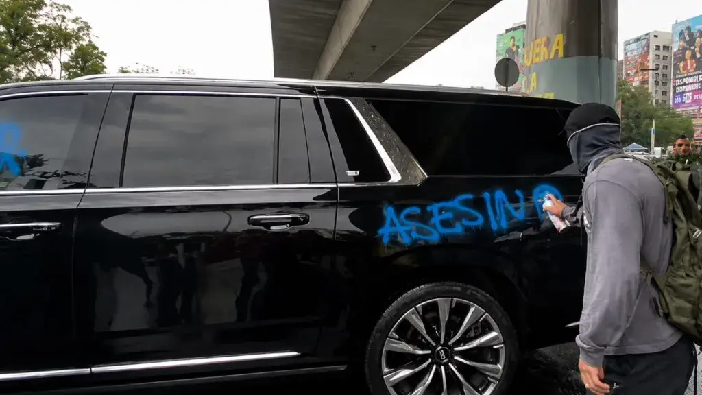 Cuauhtémoc Blanco junto a una camioneta rodeada por activistas que le gritan consignas durante una protesta antes del partido México vs Inglaterra.
