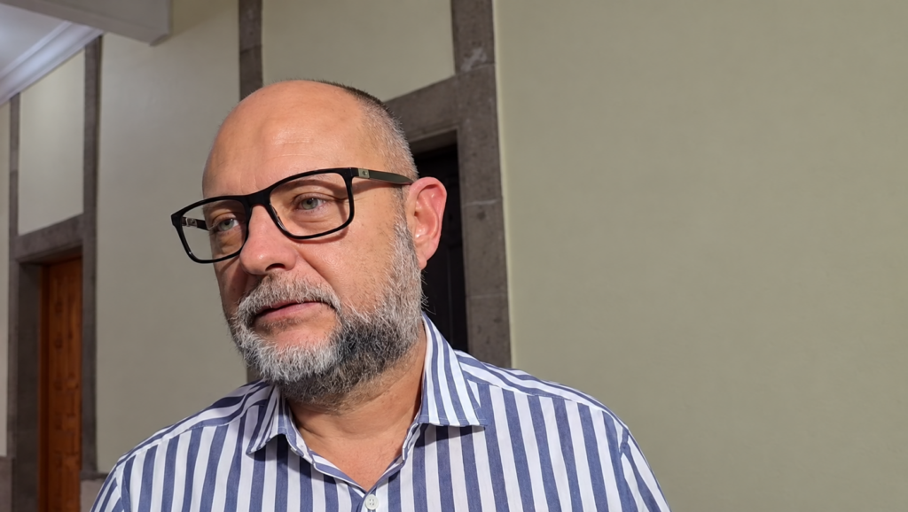 Enrique Iragorri Durán con lentes negros y camisa de rayas azules y blancas, en un espacio interior.