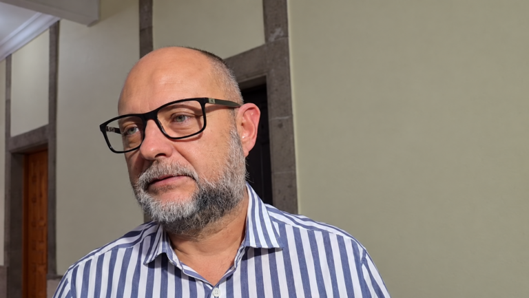 Enrique Iragorri Durán con lentes negros y camisa de rayas azules y blancas, en un espacio interior.